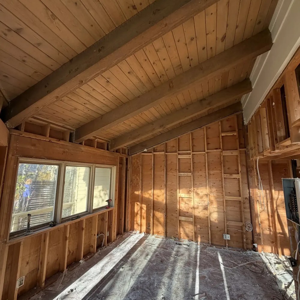 After: the same Park City room gutted to bare wall studs and subfloor, with drywall, doors, trim and flooring removed